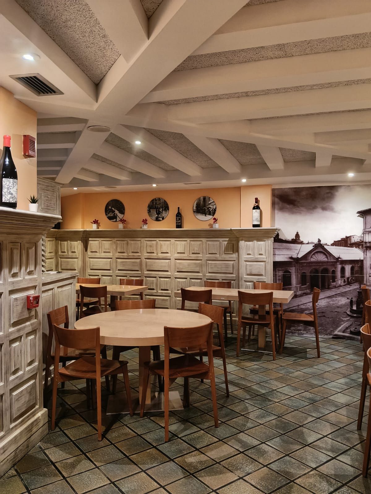 El comedor visto desde la entrada, con una mesa redonda en primer término y el mural en blanco y negro al fondo.