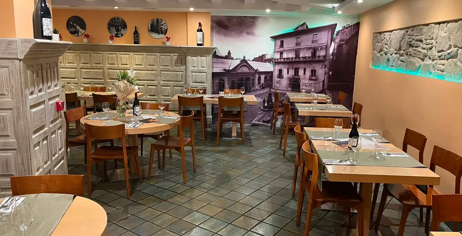 El comedor visto desde la entrada, con las mesas puestas y flores en el centro de la redonda.