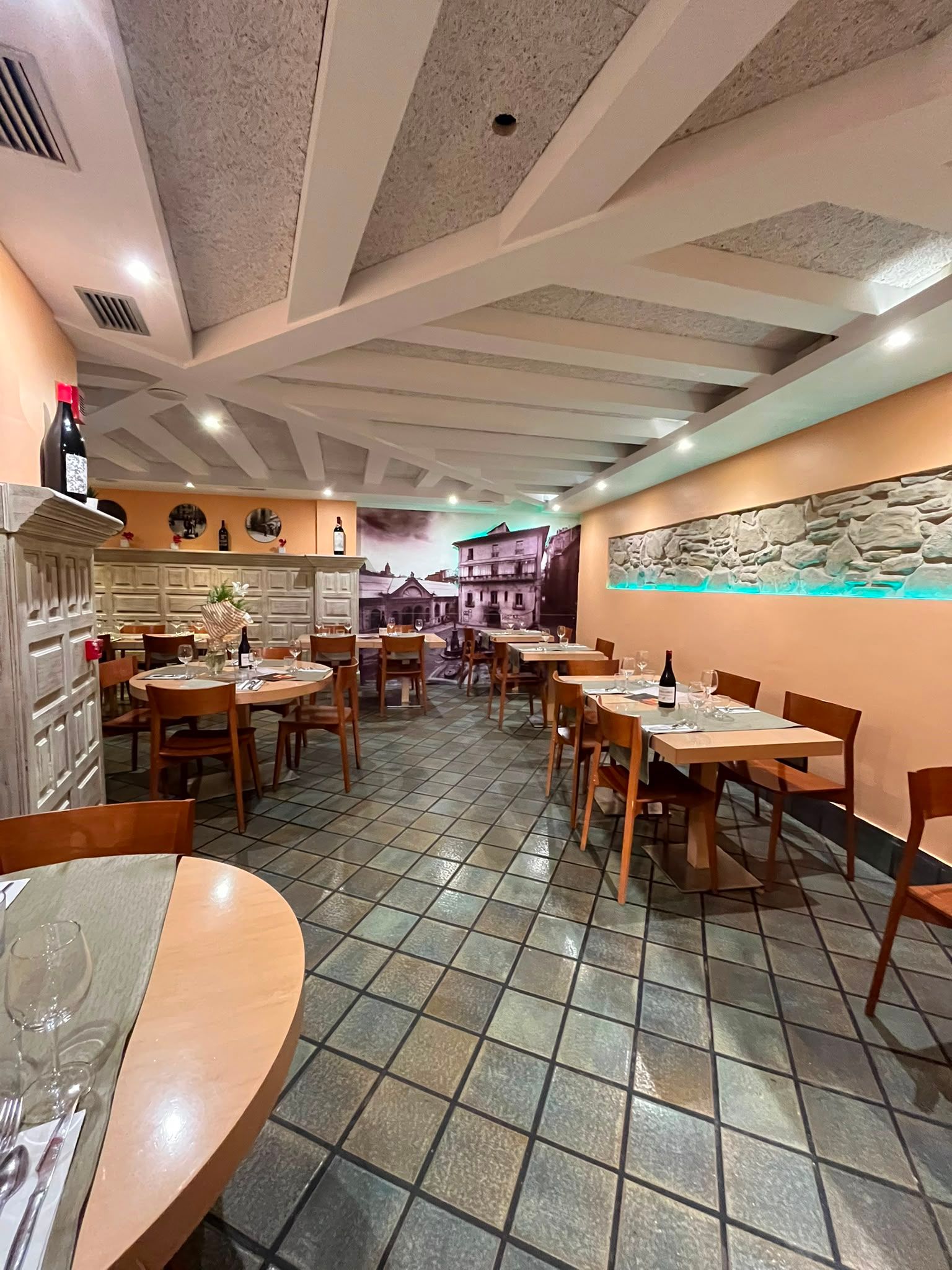 El comedor desde el otro extremo, con la mesa redonda en primer término y el muro de piedra al fondo.